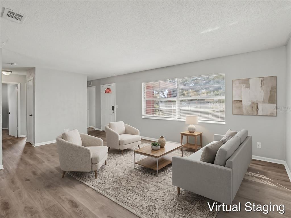 An empty living room features light gray walls, wood-look flooring, and a large window — 555 THOMAS JEFFERSON WAY, ORLANDO, FL