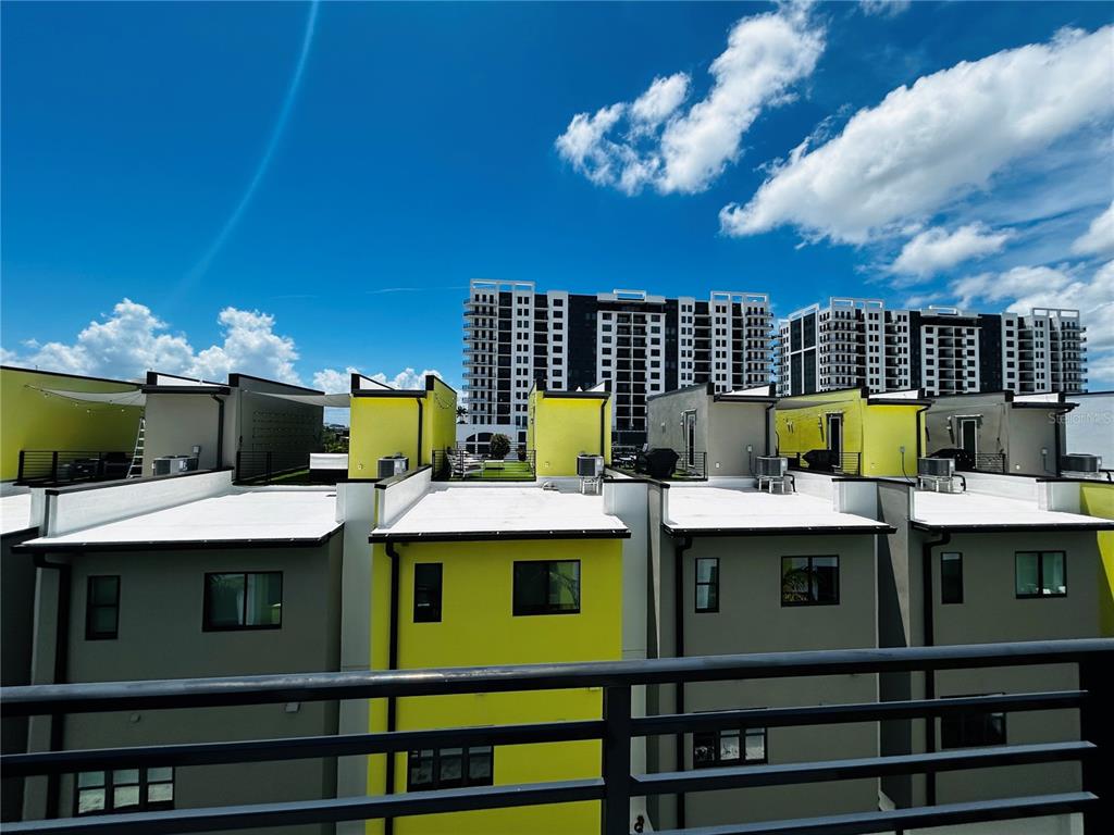 A view from a balcony overlooking the flat roofs and yellow walls of adjacent townhomes — 919 ARLINGTON AVENUE N, ST PETERSBURG, FL