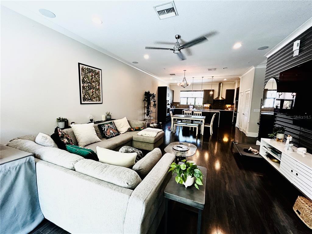 A living room with a sectional sofa flows into an open-concept kitchen with dark cabinetry — 919 ARLINGTON AVENUE N, ST PETERSBURG, FL