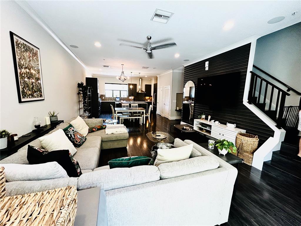 A living room with a large sectional sofa, black accent wall, and open-concept kitchen — 919 ARLINGTON AVENUE N, ST PETERSBURG, FL