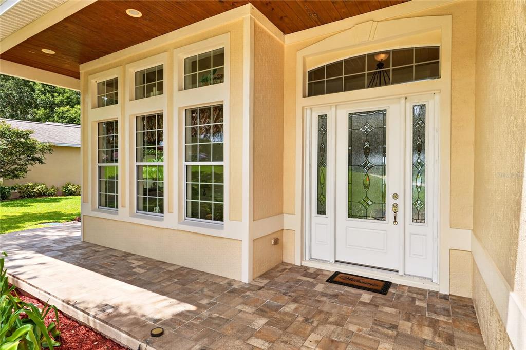 A covered front porch with tiled flooring leads to a white front door with glass inserts — 1833 SHORE LINE DRIVE, LEESBURG, FL