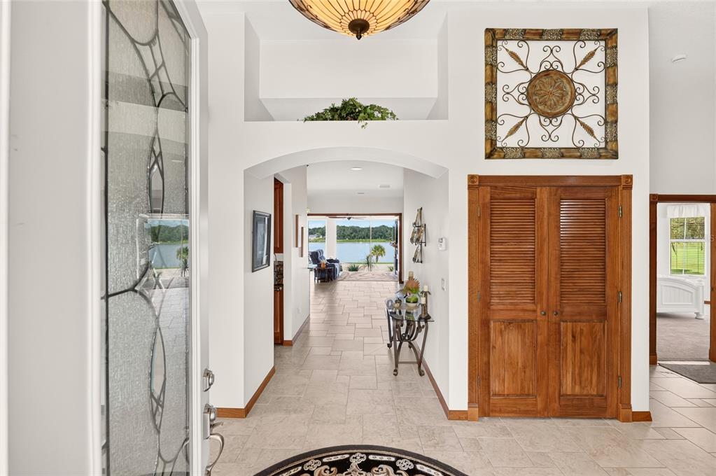 A foyer with tile floors leads to an arched hallway with a view of a lake — 1833 SHORE LINE DRIVE, LEESBURG, FL