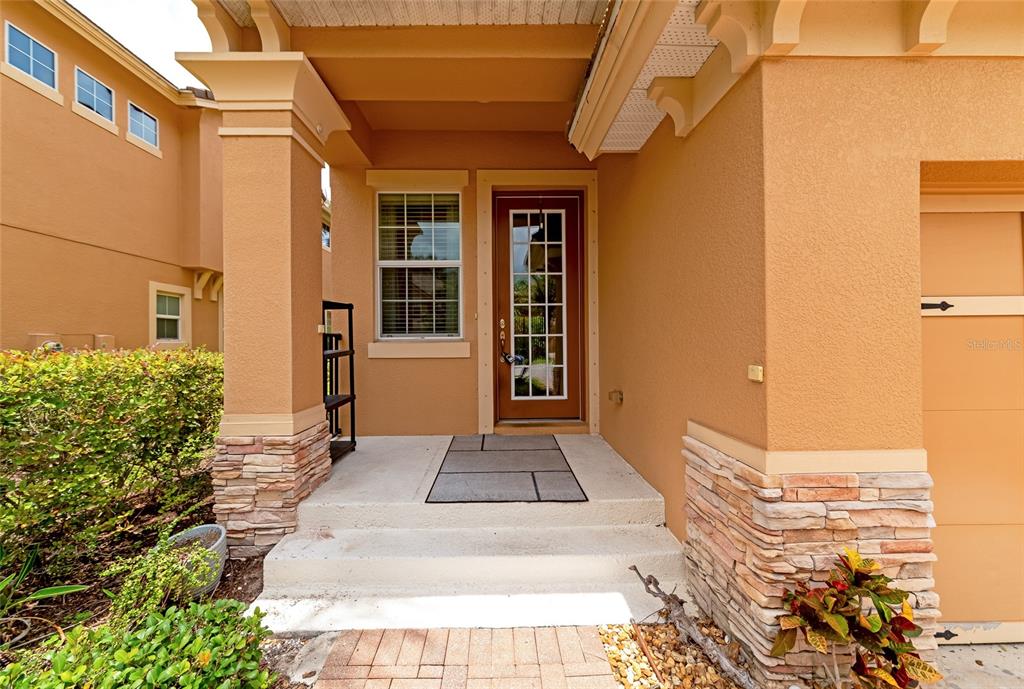 The exterior entrance features a tan stucco facade, stone accents, and a glass-paneled front door — 5519 NAPA DRIVE, SARASOTA, FL