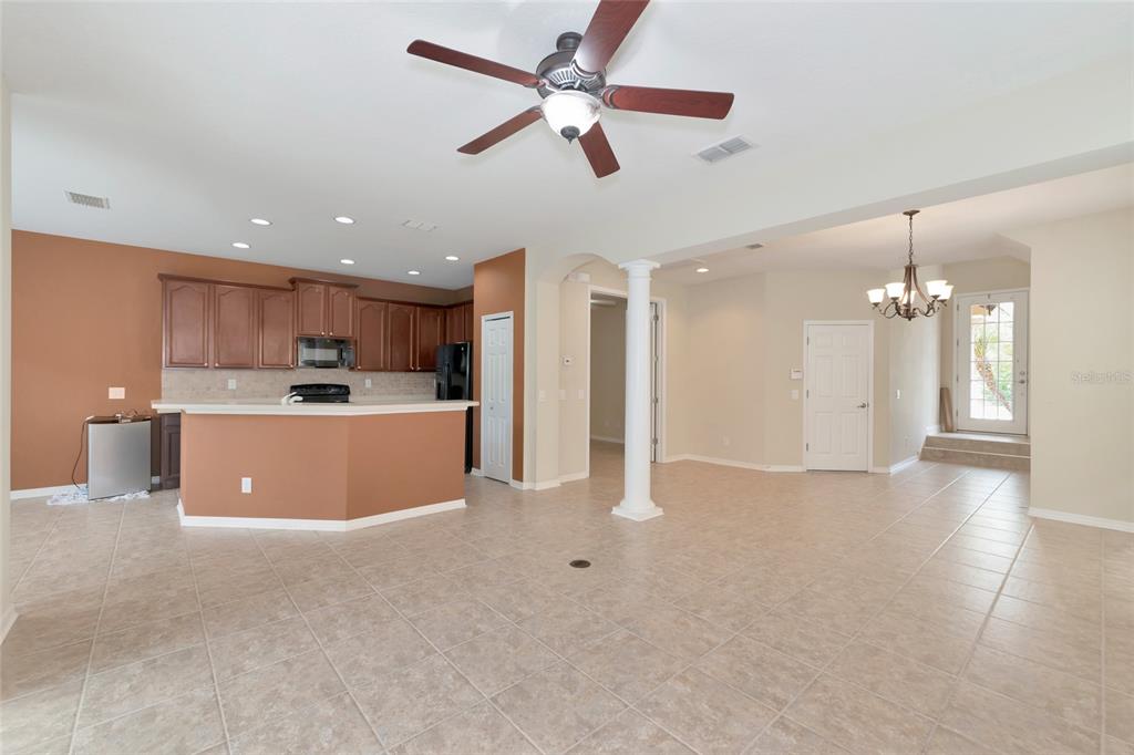 An open-concept kitchen and living area features tile flooring, brown cabinetry, and a central column — 5519 NAPA DRIVE, SARASOTA, FL