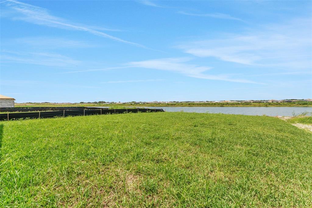 A grassy vacant lot overlooks a pond under a clear blue sky — 16930 SQUIRREL BRANCH LANE, ALVA, FL