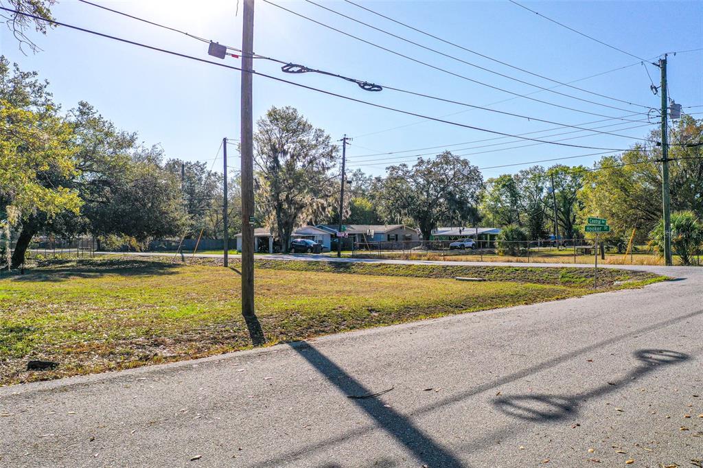 A vacant grassy lot sits at the corner of a paved street with utility poles — CENTRAL AVENUE, MULBERRY, FL