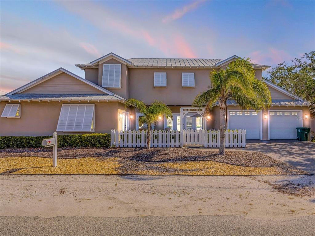 A two-story house with a white picket fence, palm trees, and a gravel front yard — 201 S COOPER STREET, NEW SMYRNA BEACH, FL