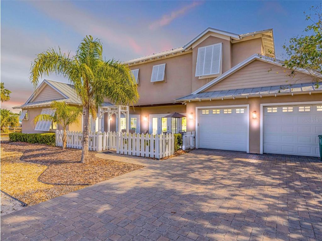 A two-story house with a paved driveway, white picket fence, and attached two-car garage — 201 S COOPER STREET, NEW SMYRNA BEACH, FL