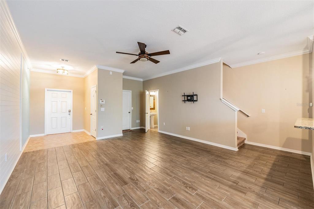 An open living area features wood-look tile flooring, a ceiling fan, and a staircase — 12039 GREENGATE DRIVE, HUDSON, FL