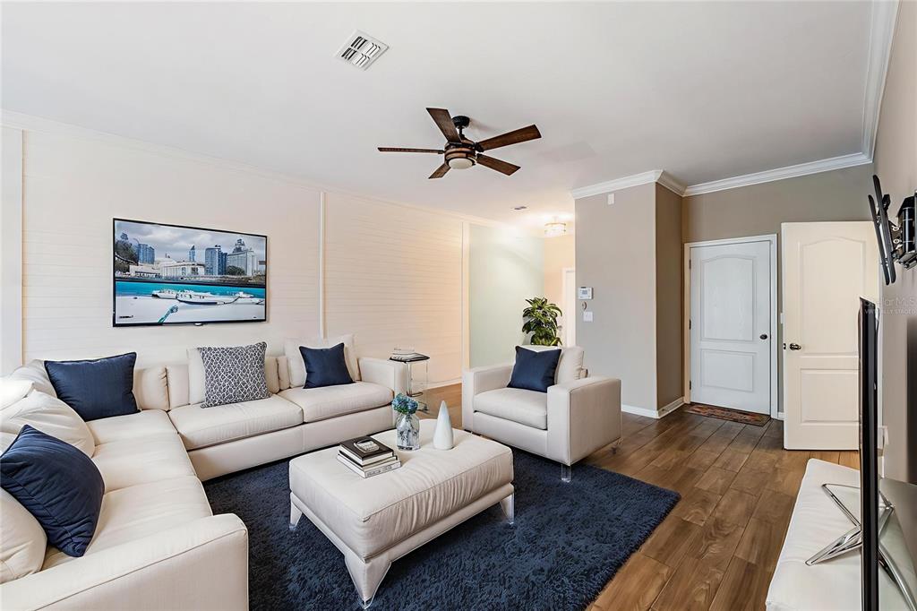 A living room features a white sectional sofa, matching armchair, ottoman, and dark blue rug — 12039 GREENGATE DRIVE, HUDSON, FL
