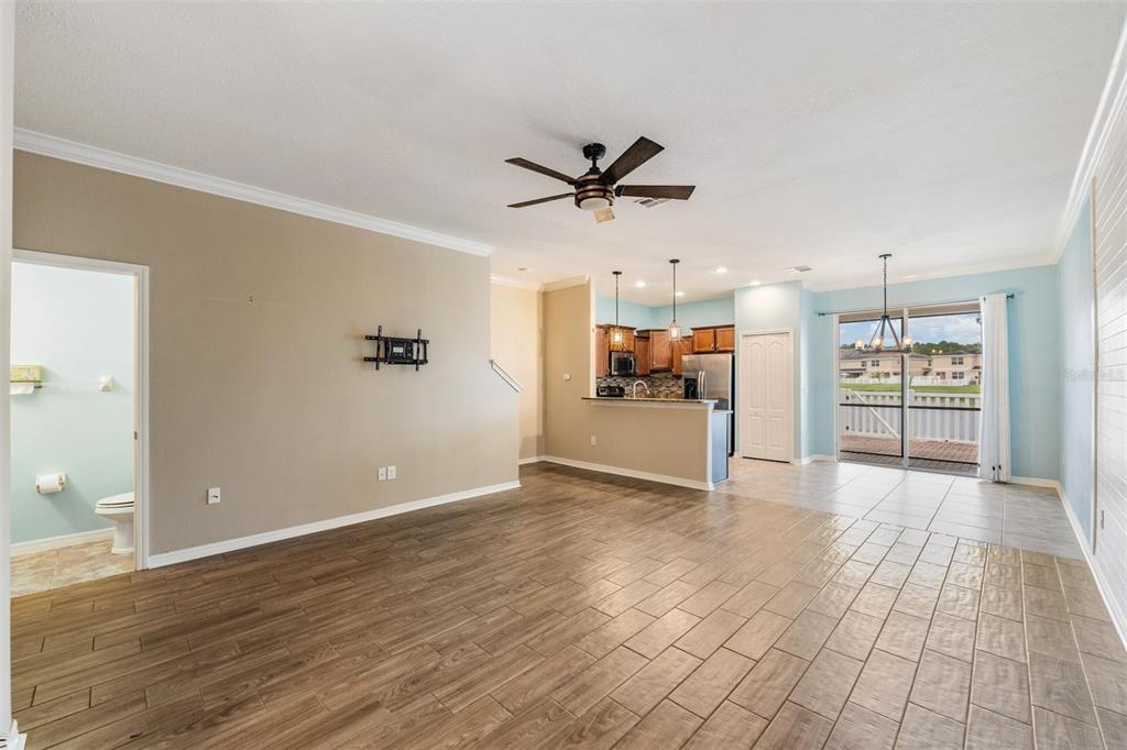 An open-concept living area with wood-look tile flooring, a kitchen, and a sliding glass door — 12039 GREENGATE DRIVE, HUDSON, FL