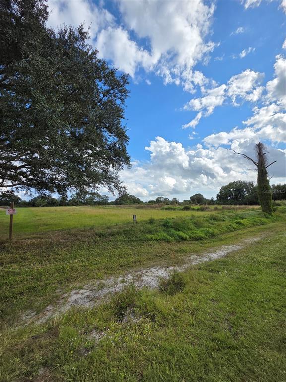 A large, grassy, open field under a blue sky with scattered clouds and large trees — 1132 NE 48TH AVENUE, OKEECHOBEE, FL