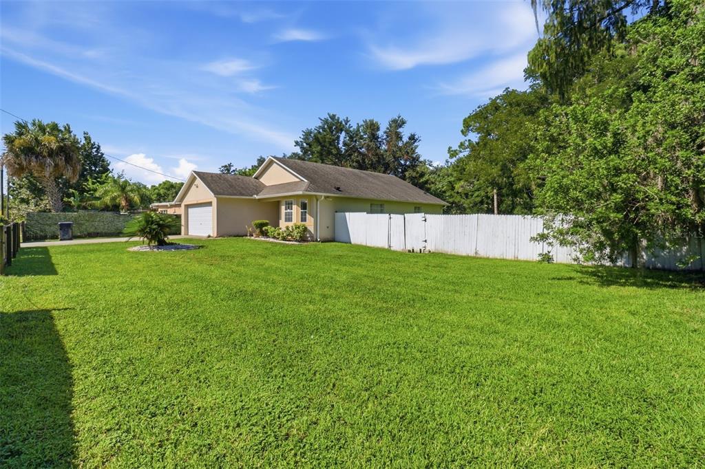 A single-story house with a garage sits behind a large green lawn and white fence — 6100 LEE LAN DRIVE, ORLANDO, FL