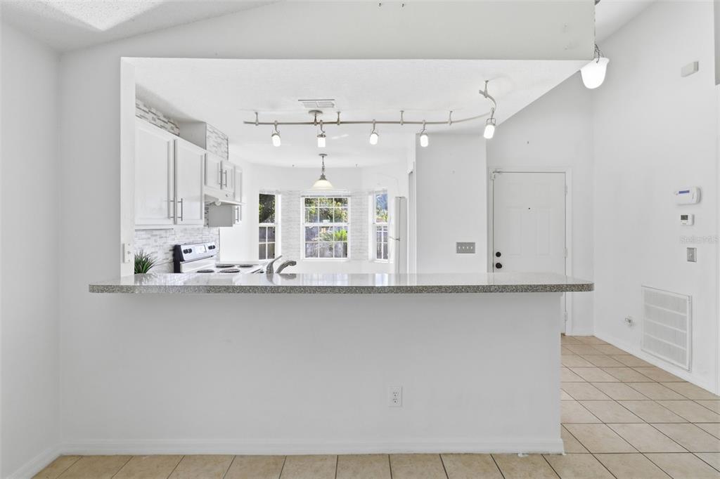 A kitchen with white cabinets, granite countertops, and a breakfast bar overlooking a dining area — 6100 LEE LAN DRIVE, ORLANDO, FL