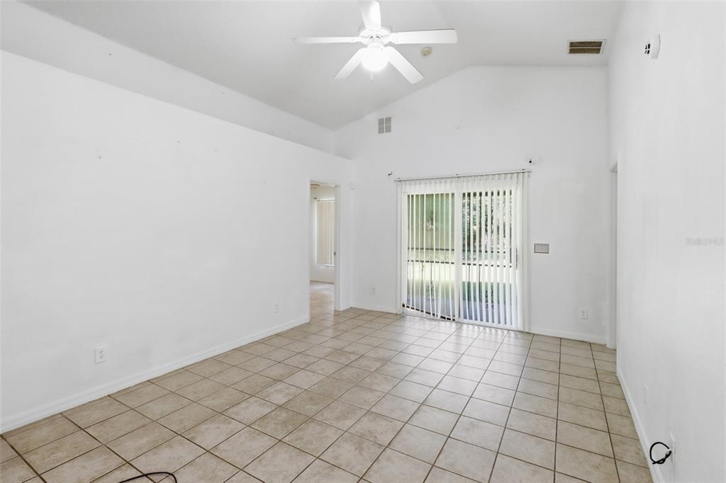 An empty room with white walls, tile flooring, a vaulted ceiling, and sliding glass doors — 6100 LEE LAN DRIVE, ORLANDO, FL