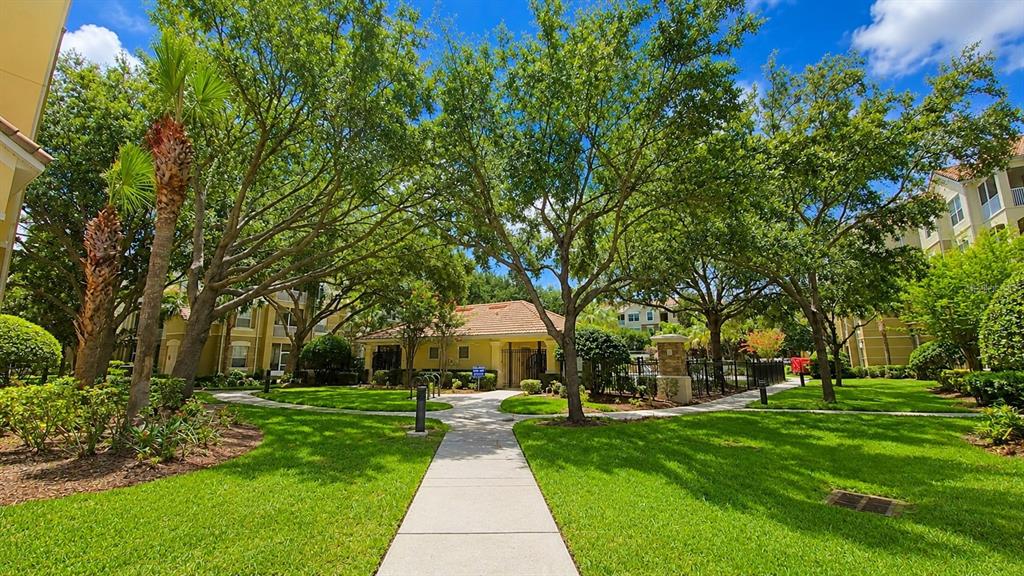 A multi-story apartment building with beige stucco walls and a covered parking area — 3326 ROBERT TRENT JONES DRIVE UNIT 209, ORLANDO, FL