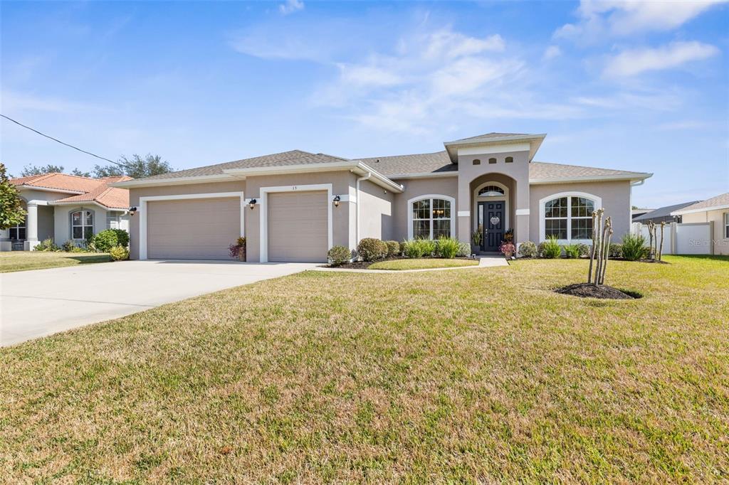 A single-story suburban house with a two-car garage, stucco exterior, and a front lawn — 15 FAIRCHILD LANE, PALM COAST, FL
