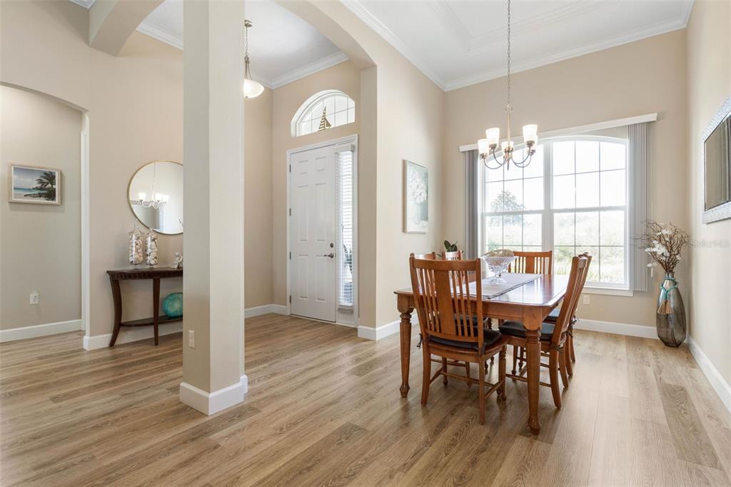 A dining area with wood-look flooring, a wooden table, and a front entryway with columns — 15 FAIRCHILD LANE, PALM COAST, FL