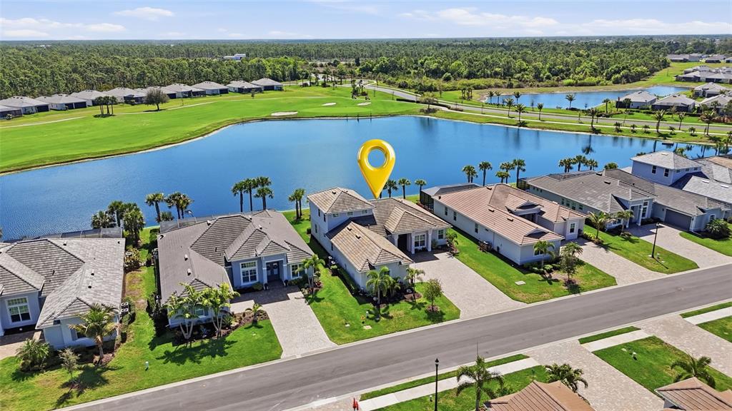 An aerial view shows a suburban neighborhood with houses situated along a large lake — 15073 RIVER BIRCH COURT, PUNTA GORDA, FL