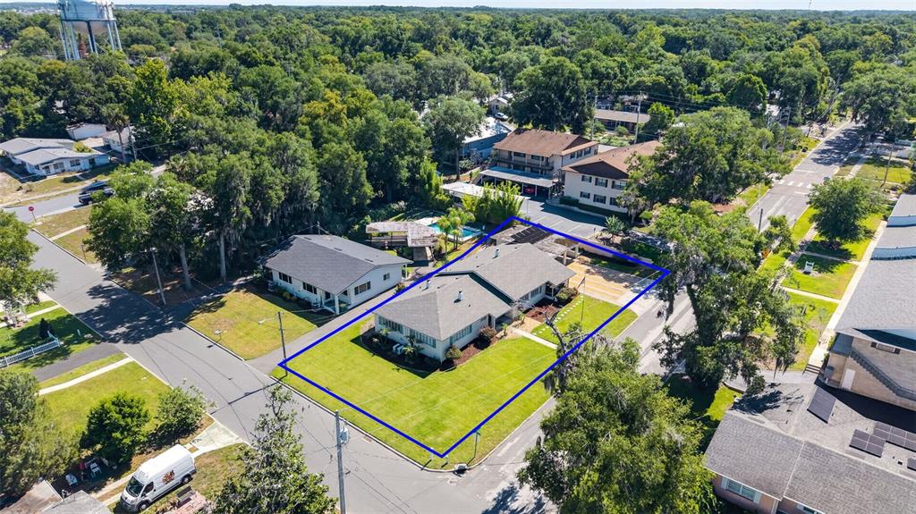 An aerial view shows a single-story house with a gray roof on a corner lot — 205 E 10TH AVENUE, MOUNT DORA, FL