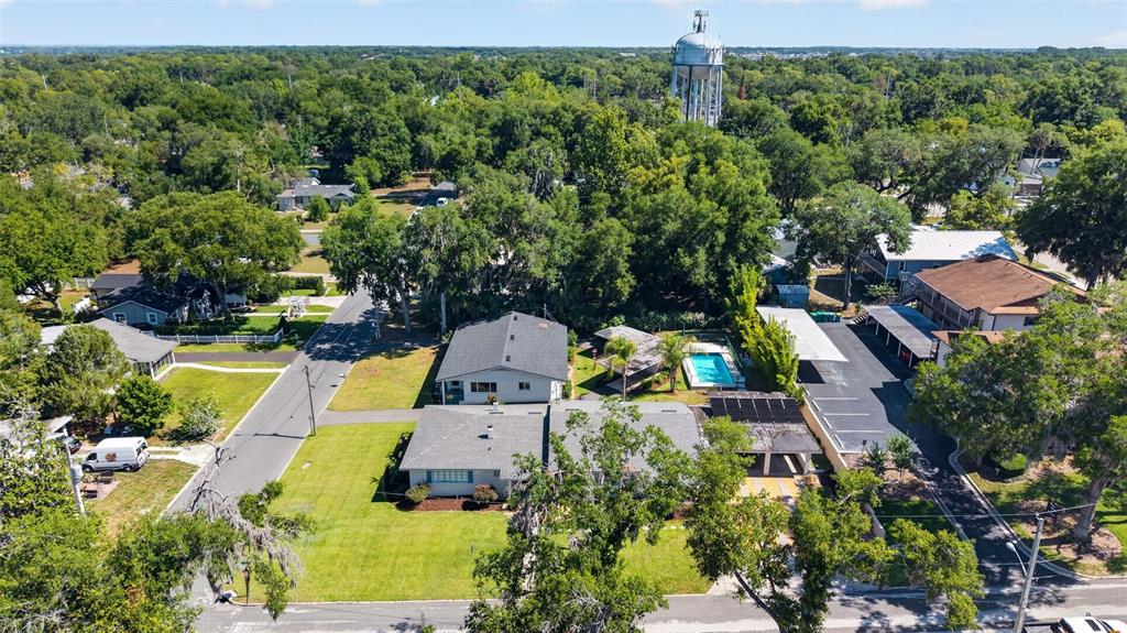 An aerial view shows a residential property with a pool, parking area, and water tower — 205 E 10TH AVENUE, MOUNT DORA, FL
