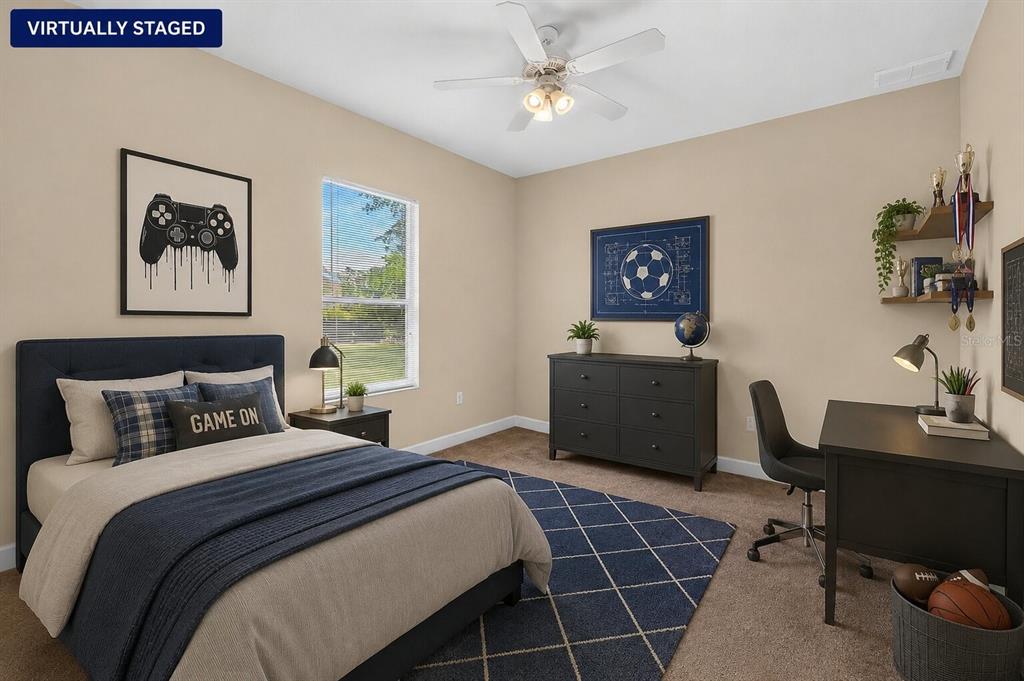 This virtually staged bedroom features a bed, desk, dresser, and a blue patterned area rug — 180 BLACK HICKORY WAY, ORMOND BEACH, FL