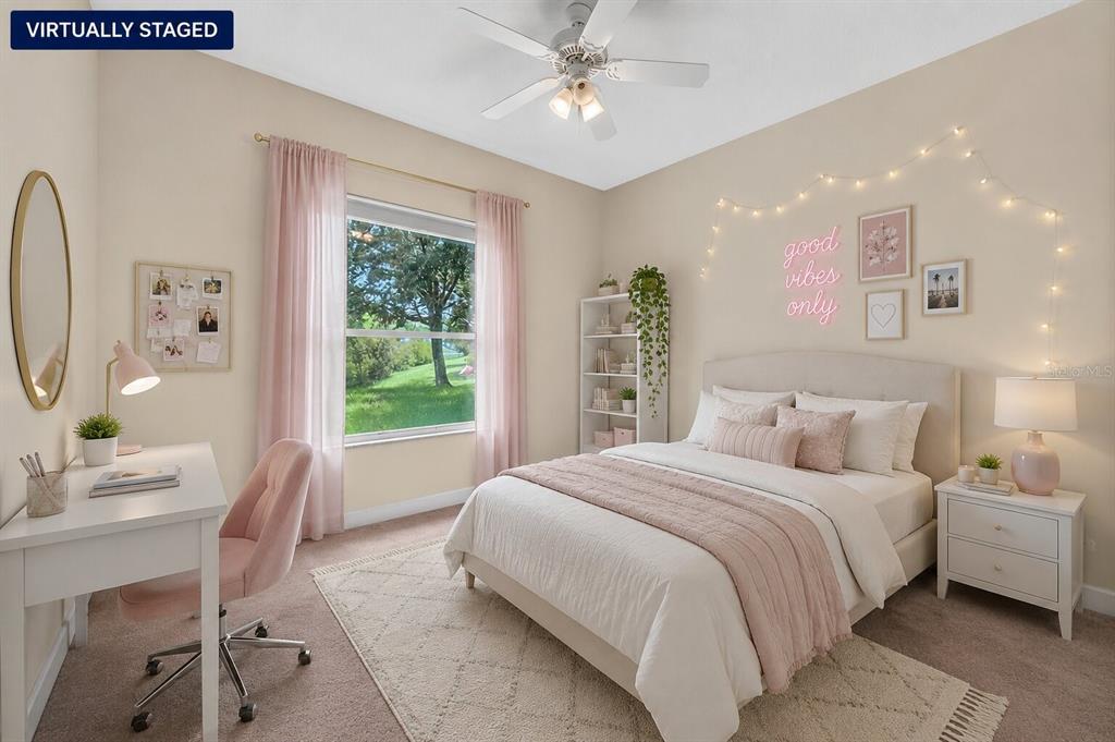 This virtually staged bedroom features a bed, desk, window with pink curtains, and wall decor — 180 BLACK HICKORY WAY, ORMOND BEACH, FL