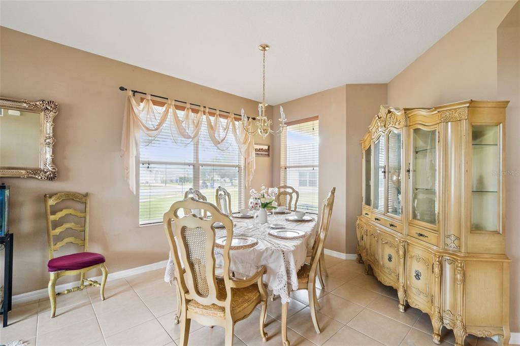 A dining room features a table with six chairs, a large hutch, and tile flooring — 3636 BRISTOL COVE LANE, ST CLOUD, FL