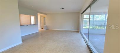 An empty room with beige carpet, light-colored walls, and a large sliding glass door — 1512 PICARDY CIRCLE, CLEARWATER, FL