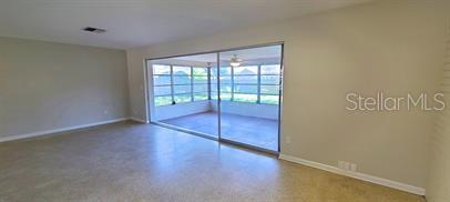 A living room with light-colored walls and flooring features a large sliding glass door — 1512 PICARDY CIRCLE, CLEARWATER, FL