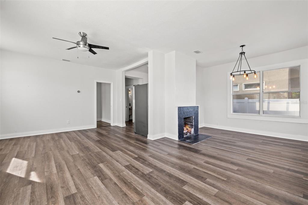 A living room with wood-look flooring, a ceiling fan, a fireplace, and a dining chandelier — 2824 5TH AVENUE N, ST PETERSBURG, FL