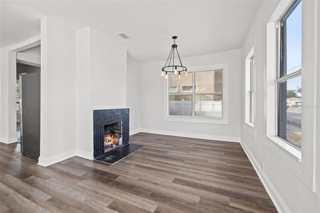 A living room features wood-look flooring, a dark herringbone-tiled fireplace, and a modern chandelier — 2824 5TH AVENUE N, ST PETERSBURG, FL