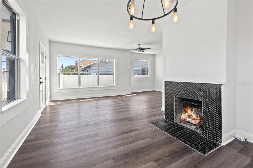 A living room with dark wood-look flooring, a black herringbone fireplace, and a modern chandelier — 2824 5TH AVENUE N, ST PETERSBURG, FL
