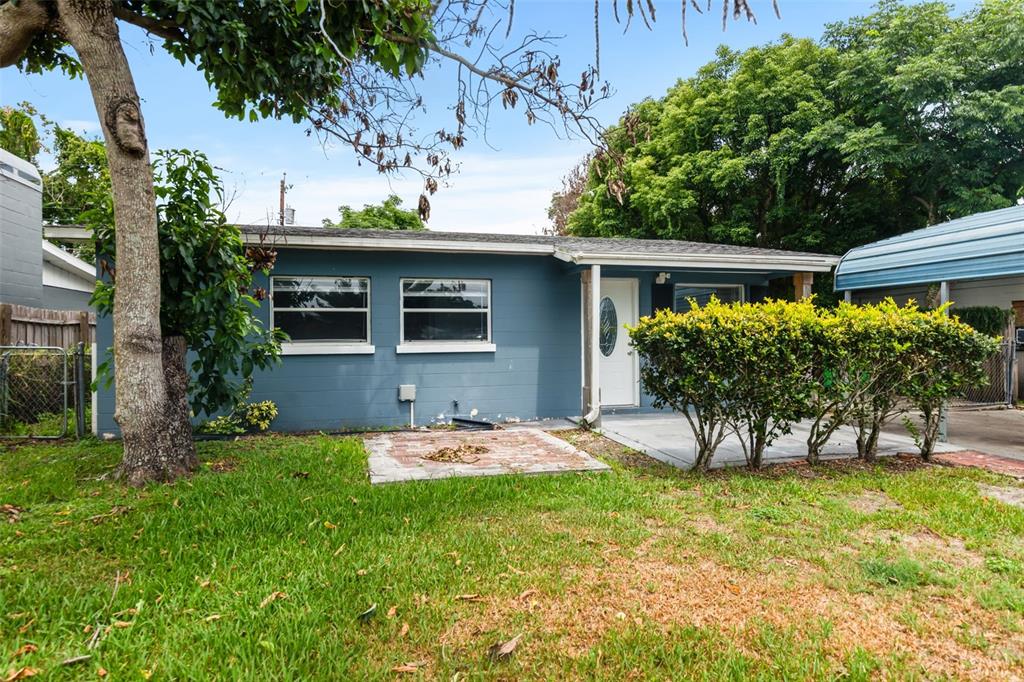 A blue house exterior features a white front door, a concrete porch, and a window — 1039 WOODLAND AVENUE, LAKELAND, FL