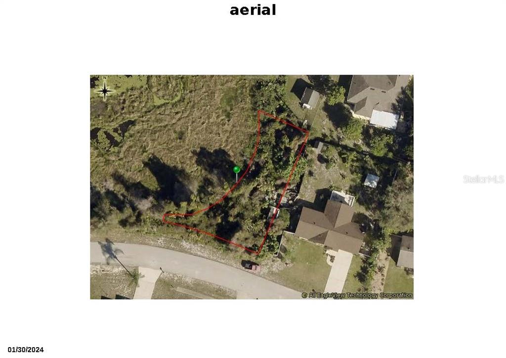 This aerial view shows a vacant, wooded lot outlined in red next to residential houses — 1342 DANDELION DRIVE, DELTONA, FL