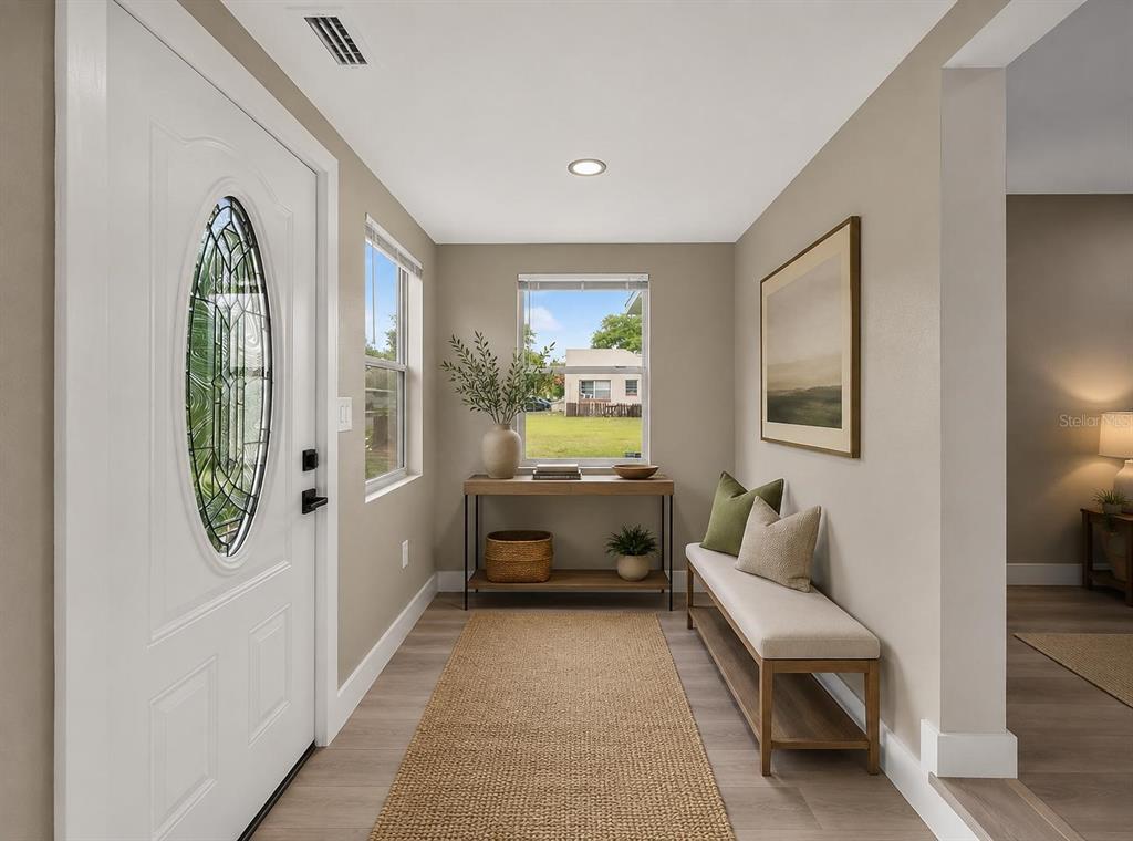 A room with light gray walls, wood-look flooring, recessed lighting, and a white front door — 1900 25TH STREET S, ST PETERSBURG, FL
