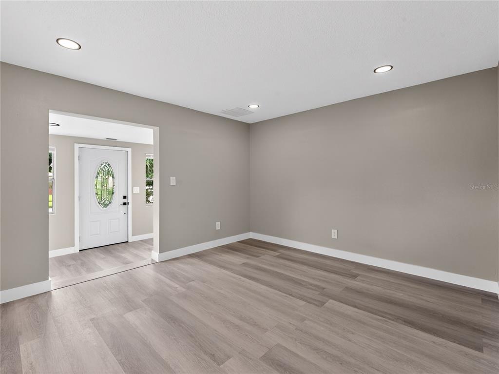 An empty room features gray walls, light wood-look flooring, recessed lighting, and a single window — 1900 25TH STREET S, ST PETERSBURG, FL