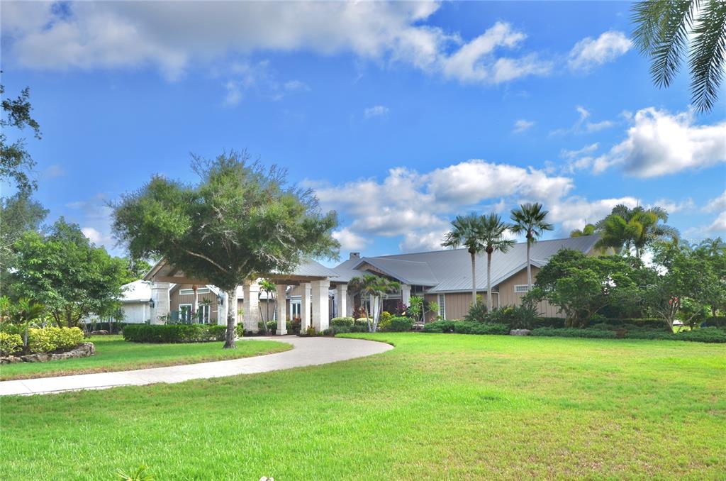 A single-story house with a metal roof, stone columns, and a curved driveway — 630 N RIVER ROAD, VENICE, FL