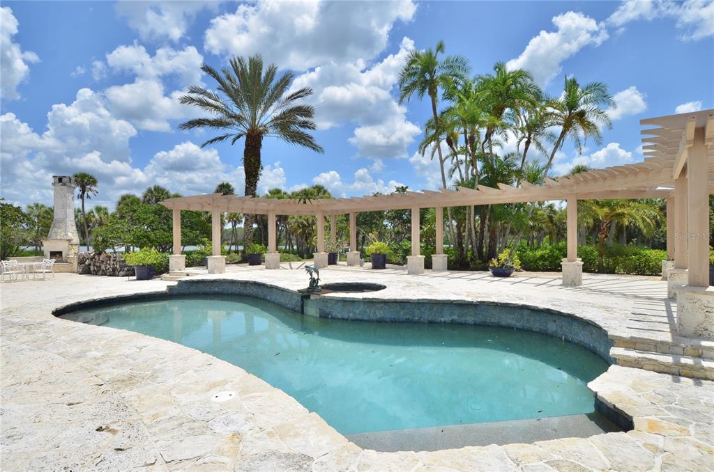 A swimming pool with a stone deck and a large wooden pergola under a blue sky — 630 N RIVER ROAD, VENICE, FL