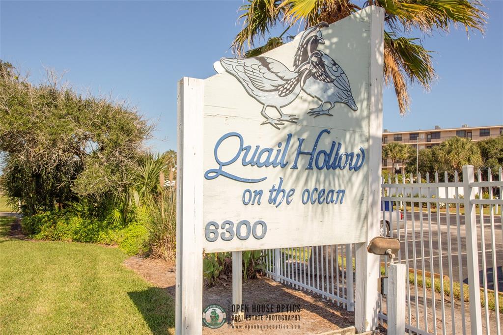 A wooden sign for Quail Hollow on the ocean stands near a white fence — 6300 A1A S UNIT A41U, ST AUGUSTINE, FL