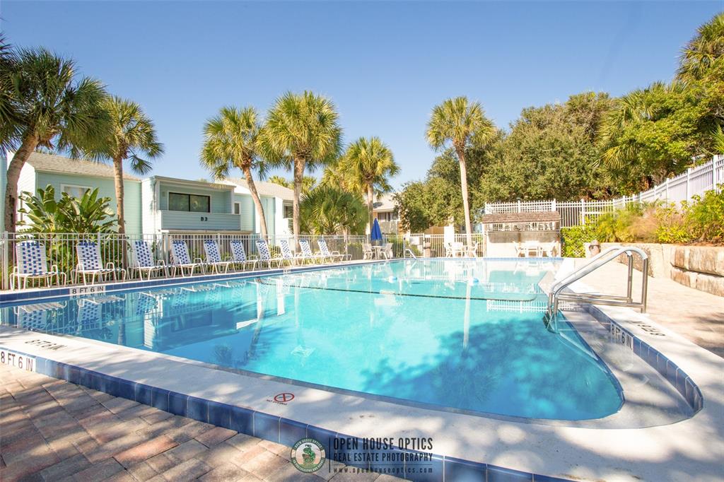 A rectangular swimming pool is surrounded by a brick deck, lounge chairs, and palm trees — 6300 A1A S UNIT A41U, ST AUGUSTINE, FL