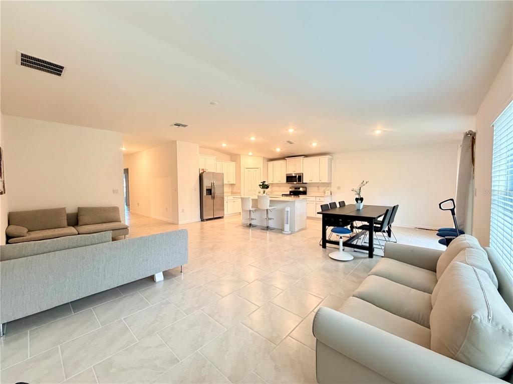 An open-concept living room and kitchen area with light tile flooring and white cabinetry — 1026 DEWHURST STREET, PORT CHARLOTTE, FL