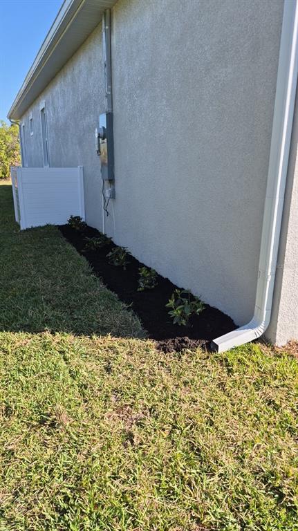 A side view of a house exterior featuring a landscaped garden bed with small plants — 122 NAOMI PL, ROTONDA WEST, FL