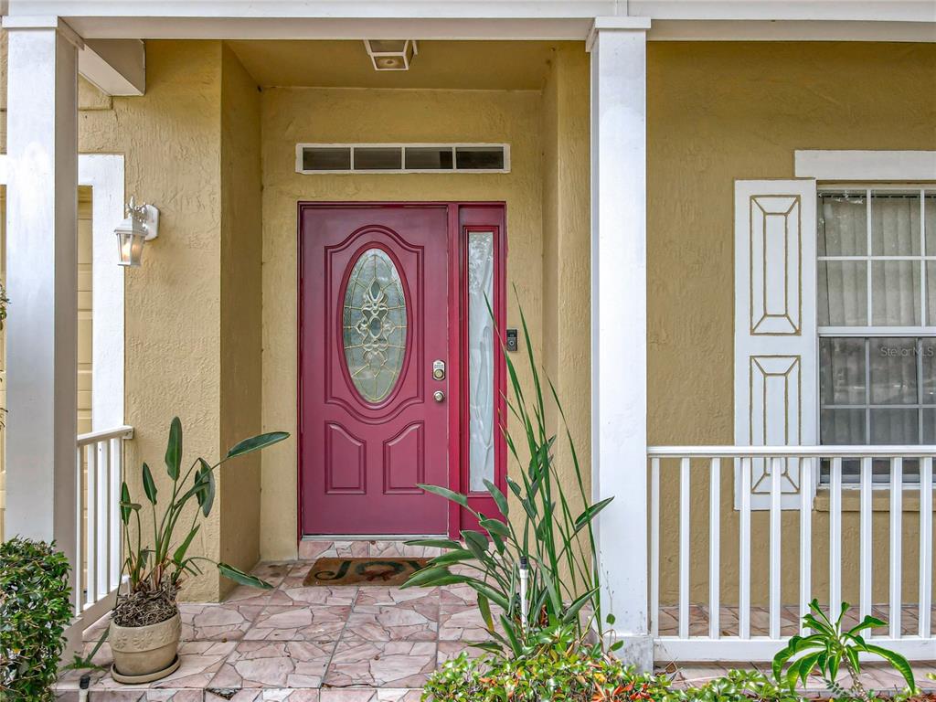 A front porch features a red door with a glass insert and a tiled floor — 7939 RIFFLE LANE, ORLANDO, FL
