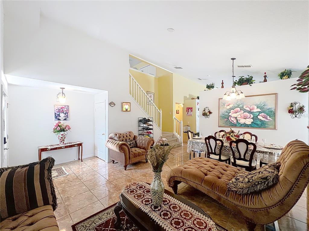 A living and dining area features tile floors, a staircase, and traditional upholstered furniture — 7939 RIFFLE LANE, ORLANDO, FL