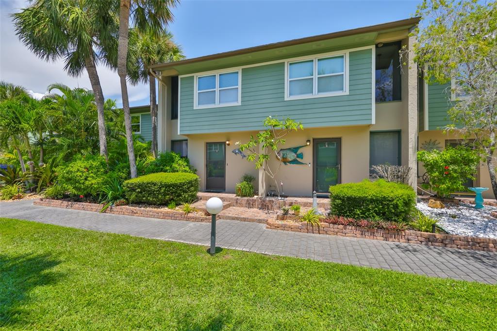 A two-story townhouse with green siding, a brick walkway, and lush landscaping — 1028 APOLLO BEACH BOULEVARD UNIT 8, APOLLO BEACH, FL
