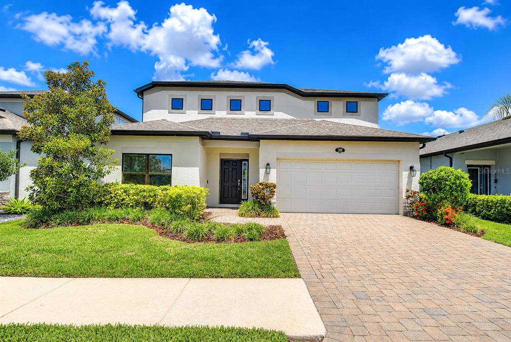 A two-story house with a paved driveway, a two-car garage, and a landscaped front yard — 1621 LEAF FLOWER LANE, LUTZ, FL
