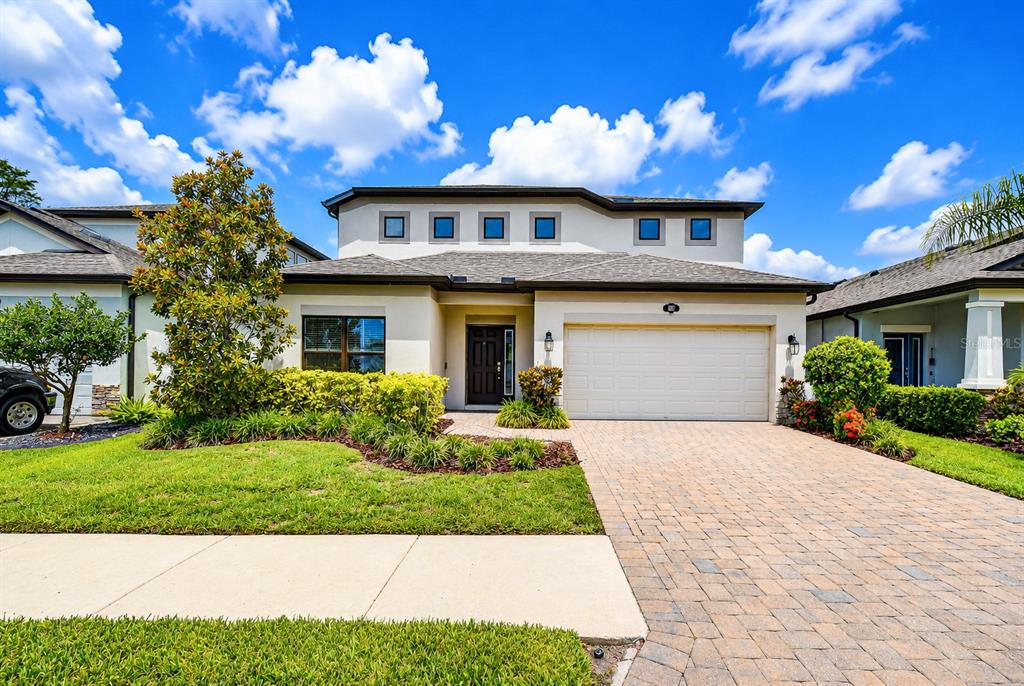 A two-story suburban house features a paved driveway, a two-car garage, and a landscaped front yard — 1621 LEAF FLOWER LANE, LUTZ, FL