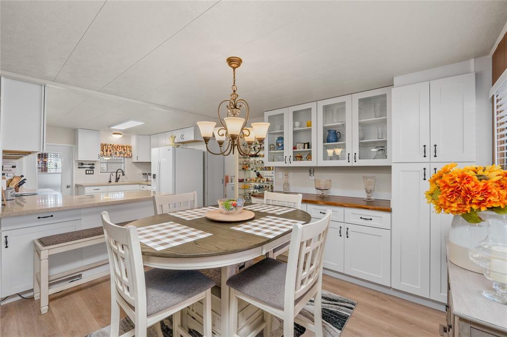 A living room and dining area feature light wood floors, white sofas, and brown walls — 288 SALEM AVENUE UNIT 3, PALM HARBOR, FL