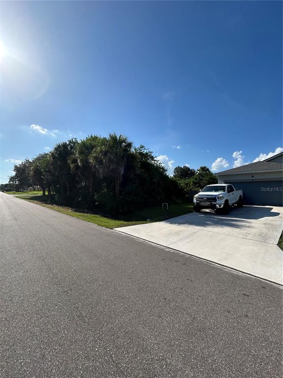 A white pickup truck is parked on a concrete driveway next to a vacant lot — 171 LAGOON STREET SW, PALM BAY, FL